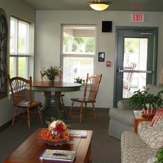 A cozy living room with a table, chairs, and a sofa adorned with plants and decor.