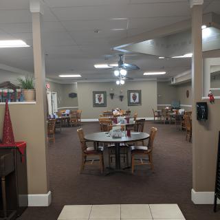 A cozy dining room with several tables and chairs arranged neatly under ceiling fans.