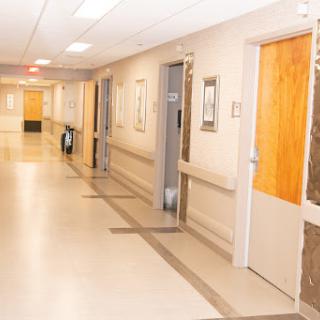 A well-lit corridor in a hospital, featuring several doors leading to different rooms.