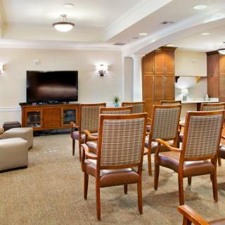 A cozy seating area with wooden chairs arranged facing a television in a warmly decorated living room.