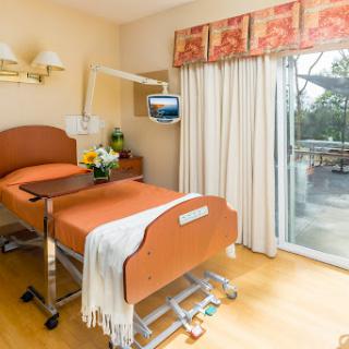 A cozy hospital room featuring a patient bed, natural light from the window, and a soft color palette.