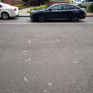 A black car parked alongside a white car on a city street.