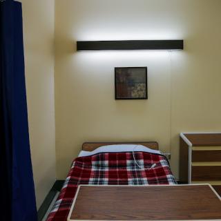 A simple room with a bed, a light fixture, and minimal furniture.