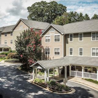 A multi-story residential building surrounded by trees and a small driveway.