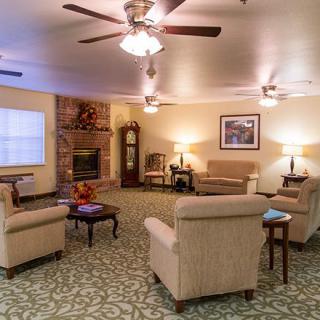 A cozy living room with multiple sofas, ceiling fans, and a fireplace.