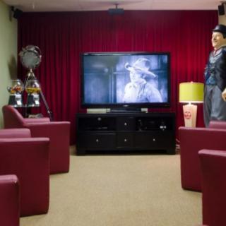 A cozy home theater setup with red chairs and vintage decor, featuring a large TV for movie watching.