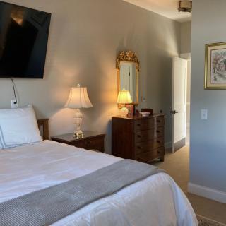 A cozy bedroom with a neatly made bed, wall-mounted television, and warm lighting from bedside lamps.