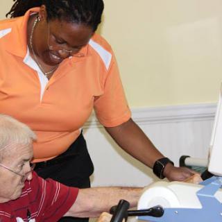 A caregiver assists an elderly person with a therapeutic device.