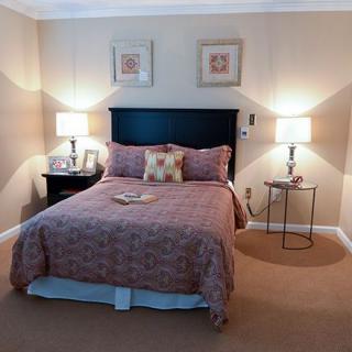 A cozy bedroom with a neatly made bed between two bedside tables and lamps.