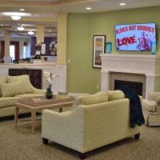A cozy living room with sofas, a fireplace, and a television displaying a movie poster.