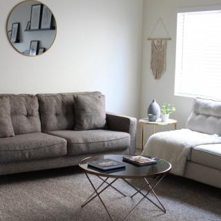 A modern minimalist living room with a gray sofa, round coffee table, and wall decor.