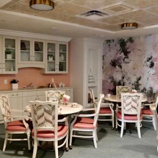 A beautifully decorated dining area featuring a kitchenette, floral wallpaper, and elegant furniture.