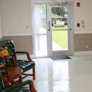 A clean indoor waiting area with chairs and an entrance door leading outside.
