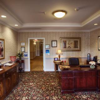 A neatly organized office space with a wooden desk, decorative carpet, and framed art on the walls.