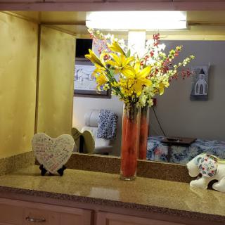 A beautifully arranged vase of yellow flowers sits on a countertop, complemented by a heart-shaped decoration and soft lighting.