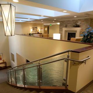 A spacious and inviting interior lobby featuring elegant lighting and a gracefully curved staircase.