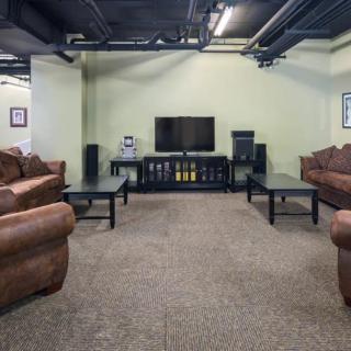 A spacious living room with multiple sofas facing a large television.