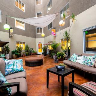 A cozy indoor patio featuring seating areas with cushions, surrounded by plants and modern decor.