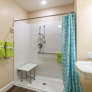A modern and accessible shower space featuring a vibrant curtain and neatly organized towels.
