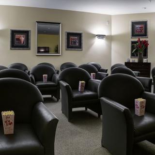 An empty lounge area with rows of comfortable chairs and popcorn boxes placed on each seat.