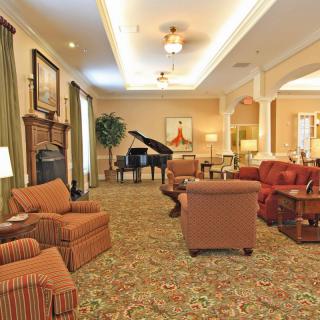 A spacious, elegantly decorated living room with comfortable seating and a grand piano.
