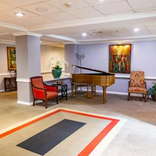 A cozy lobby area featuring a grand piano, elegant seating, and decorative artwork.