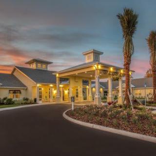 A well-lit building entrance with palm trees at dusk.