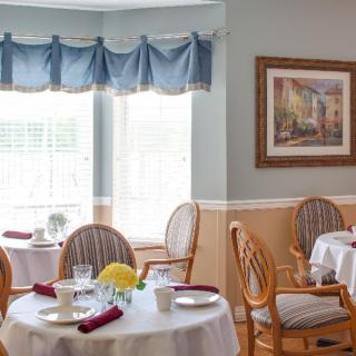 A cozy dining area with elegantly set tables and decorative artwork.