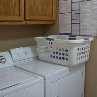 A laundry room with a washing machine, dryer, and a laundry basket on top.