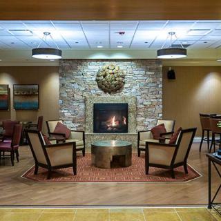 A cozy lounge with a fireplace, surrounded by comfortable chairs and a stone wall.