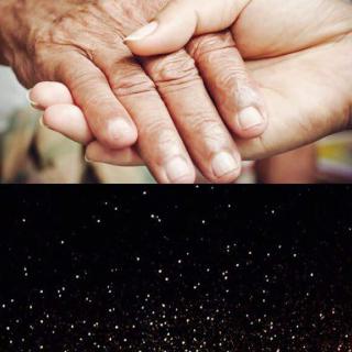 A comforting gesture of holding hands under a backdrop of shimmering lights.