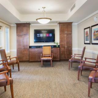 A modern waiting room featuring arranged chairs, a television, and decorative artwork on the walls.