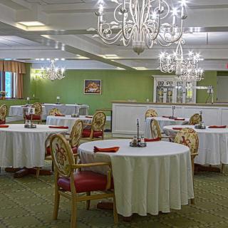 An elegant dining room with chandeliers and round tables set for a formal event.