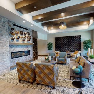 A modern living room with elegant decor, featuring stylish seating, a stone fireplace, and artistic wall elements.