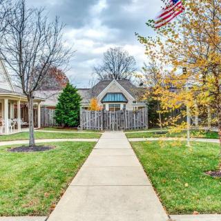 A cozy house with a pathway, surrounded by trees in autumn colors under a cloudy sky.