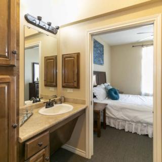 A view of a bathroom vanity area leading into a cozy bedroom.