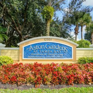Entrance sign of Aston Gardens at Pelican Pointe surrounded by lush landscaping.