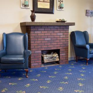 A cozy living room setting featuring blue armchairs, a brick fireplace, and decorative accents.