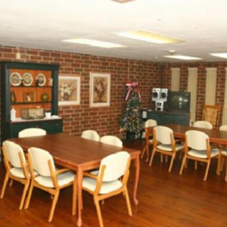 A cozy dining room with wooden tables and chairs, adorned with a festive Christmas tree and brick walls.