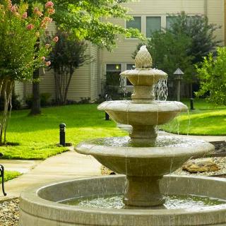 A beautiful multi-tiered fountain in a lush garden setting.