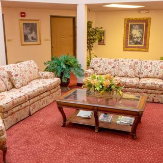 A cozy living room with floral sofas and a wooden coffee table adorned with flowers.