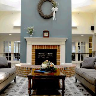 A cozy living room with a fireplace, adorned with a wreath and flanked by two sofas.