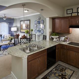 Modern open-plan kitchen and living room with wood cabinets and granite countertops.