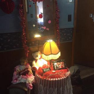 A cozy, Valentine's Day-themed table setting with a lamp, teddy bear, and decorative elements.