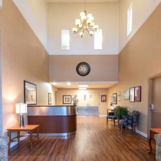 A spacious and welcoming lobby featuring a reception desk, elegant chandelier, and comfortable seating.