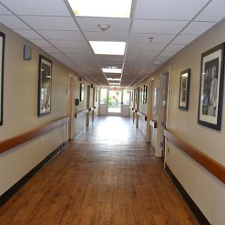 A well-lit hallway featuring wooden flooring and framed artwork on the walls.