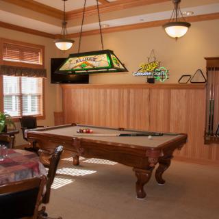 A cozy game room with a classic pool table and stylish wood paneling.