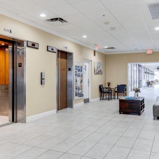 A modern lobby featuring elevator doors, a seating area, and a spacious hallway.