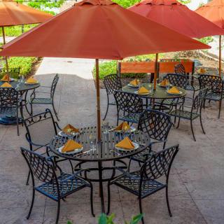 An outdoor dining area with tables and chairs under orange umbrellas.