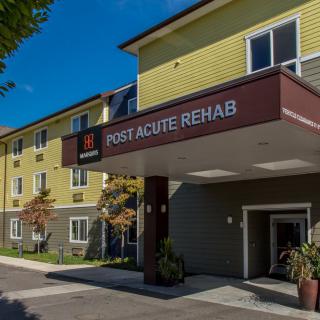 A healthcare facility with a sign for post acute rehab visible at the entrance.